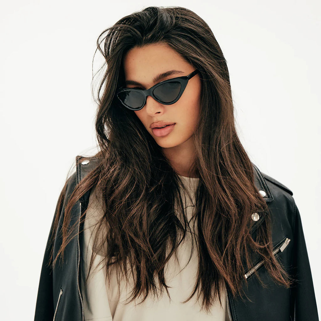 This shows a woman with brunette hair. It is long and shiny. She is wearing sunglasses and she looks stylish and put together. 